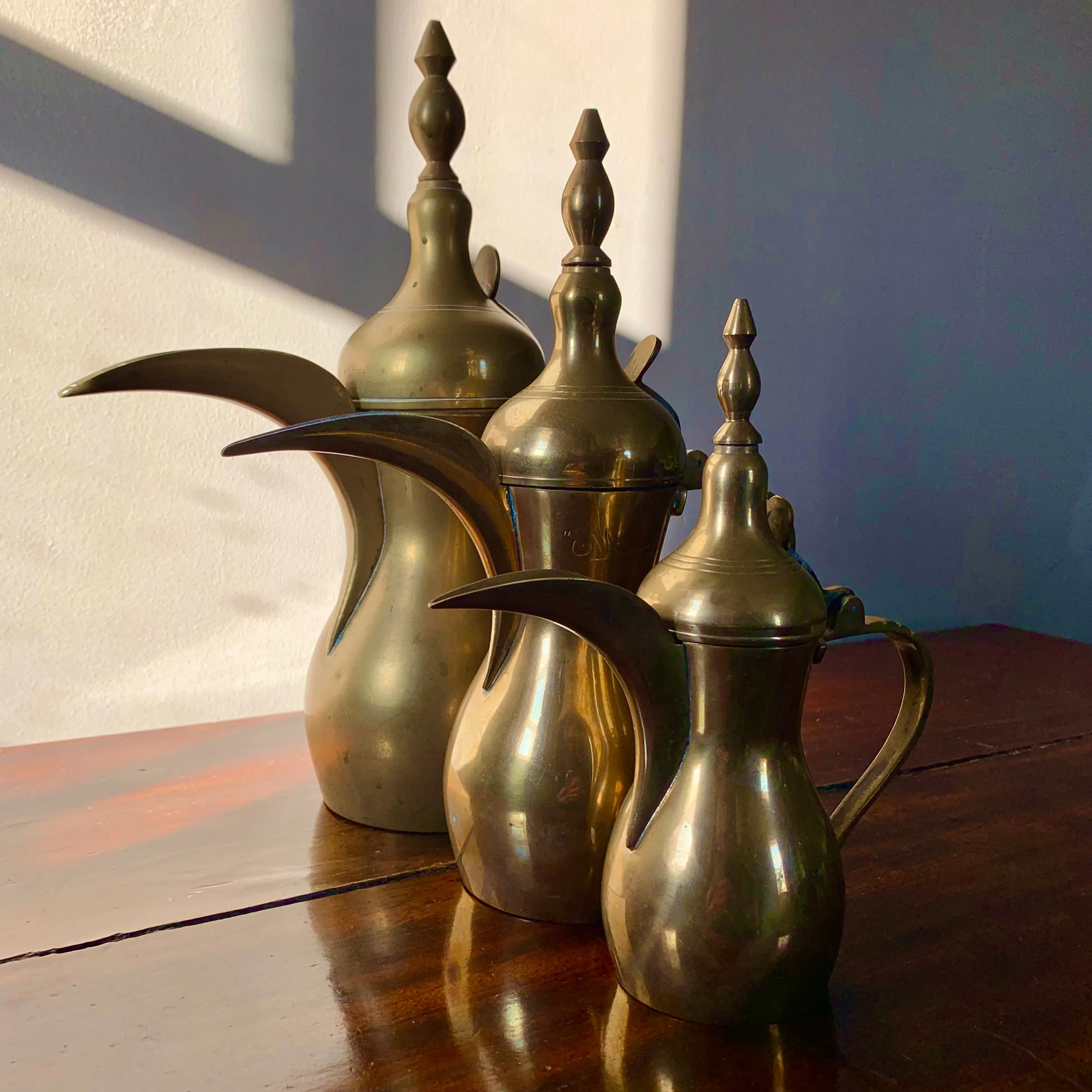 A striking set of three graduated size brass coffee pots