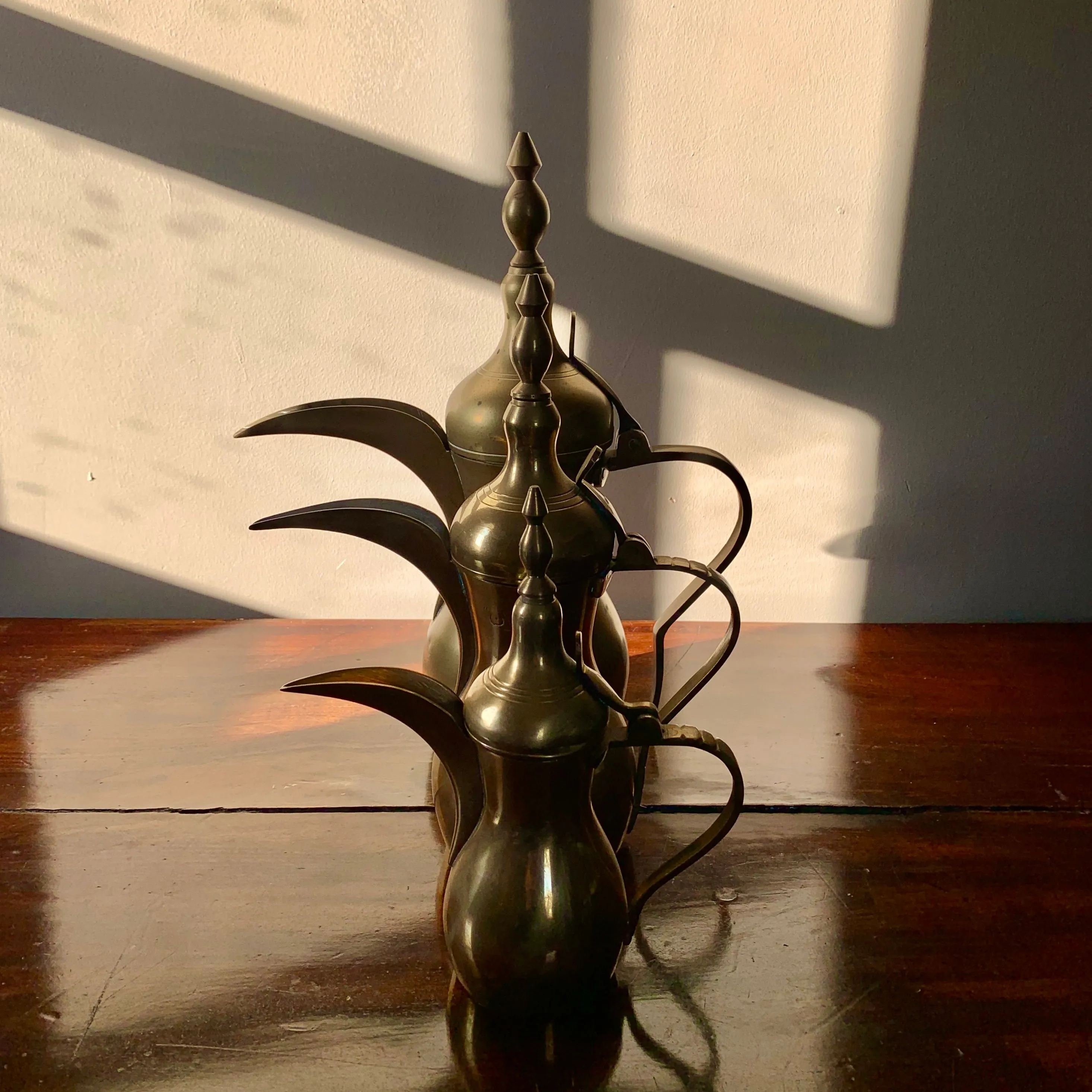 A striking set of three graduated size brass coffee pots