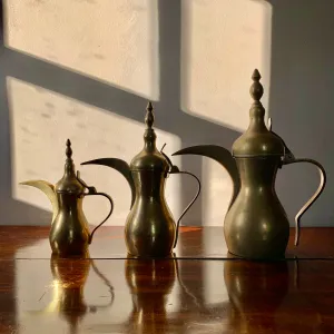 A striking set of three graduated size brass coffee pots